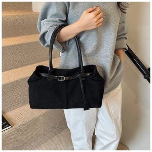Detailed shot of large black matte tote bag with glossy leather handles on model