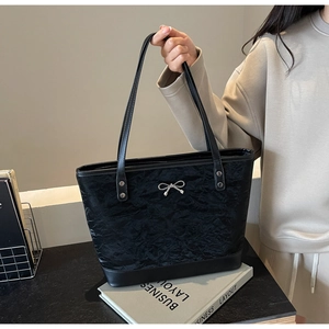 Détail du sac cabas plissé noir avec nœud argenté et fine bandoulière élégante