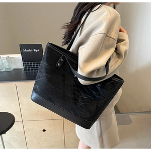 Détail du grand sac cabas noir montrant la texture plissée unique et la bandoulière fine
