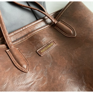 Close-up of vintage dark brown faux leather tote bag with FASHION & BAGS leather label
