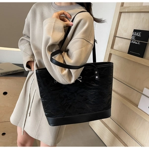 Détail d'un grand sac cabas noir avec texture en cuir froissé et nœud argenté décoratif
