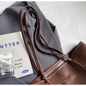 Close-up of vintage dark brown tote bag with gold embossed logo and oil wax leather texture