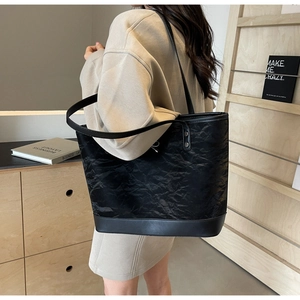 Détail du sac cabas noir avec texture plissée unique et finitions en cuir lisse