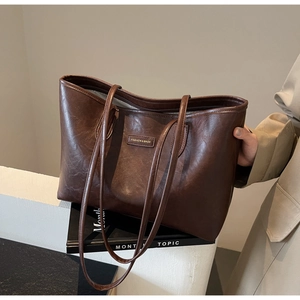 Detail of dark brown tote bag featuring retro oil-wax texture and metal fashion label