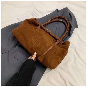 Detail shot of brown faux suede tote bag with cylinder handles and leather strap buckle