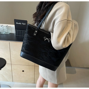 Détail d'un sac cabas noir avec texture plissée et nœud métallique argenté