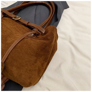 Detail of matte brown suede texture with dark leather straps and gold metal hardware