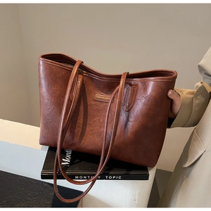 Detailed view of the vintage brown leather texture and fashion brand tag on the tote bag