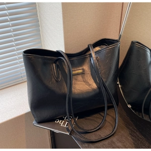 Detail of black leather tote bag with vintage texture and fashion label on wooden table
