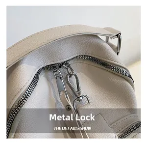 Detail of silver hardware clasp and zipper on white lychee pattern leather backpack