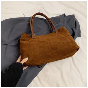Detail of brown suede tote bag with smooth handles shown in a professional setting