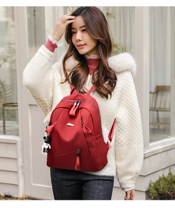 Detail of dark red high-capacity backpack with cute bear charm worn by a model
