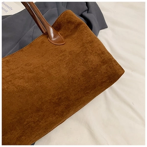 Detail of dark brown tote bag showing matte suede texture and leather handle stitching