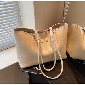Detailed macro view of the cream tote bag's textured leather and fashion logo stitching