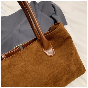 Detail of brown corduroy tote bag showing contrast leather handle and metal hardware