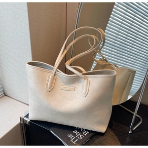 Close-up of cream textured leather tote bag showing the embossed square logo detail