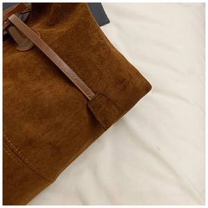 Close-up of deep brown suede tote bag showing premium stitching and texture details