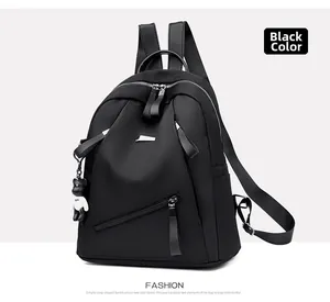 Detail of black waterproof nylon backpack featuring diagonal zipper pocket and bear charm