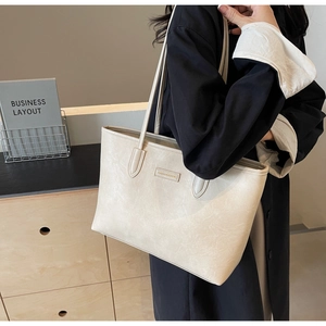 Detail of minimalist cream large tote bag with textured surface and slim shoulder straps