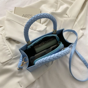 Detail of light blue crossbody bag interior with woven handle and zippered pocket