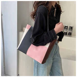 Detail shot of a large color-block patchwork tote bag in pink and grey matte leather