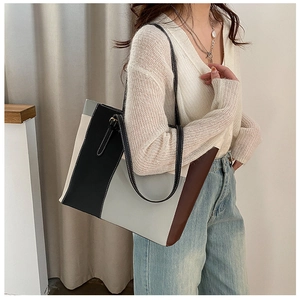 Detail of color-block tote bag with vertical stitching and fine white thread embroidery