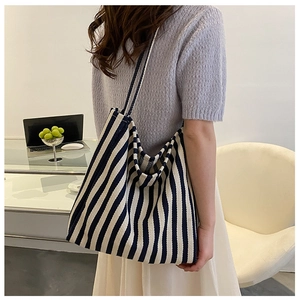 Detailansicht einer großen blau-weiß gestreiften Canvas-Tasche, getragen von einem Modell