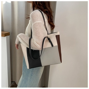 Detail view of large patchwork tote bag featuring contrast stitching and leather texture
