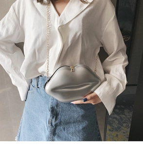 Detail of silver lip-shaped crossbody bag with a fine gold chain and metallic finish