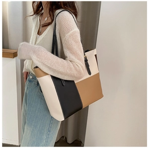 Detailed view of large patchwork tote bag in beige, black, and tan PU leather with dual straps