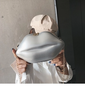 Close-up of shiny silver lip-shaped clutch with gold metal chain strap and top zipper