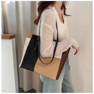 Detail of color-block PU leather tote bag with white stitching and long shoulder straps