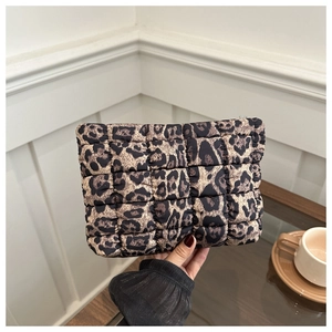 Close-up of leopard print quilted clutch bag held by hand in a cozy lifestyle setting