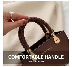 Detail of dark brown crocodile pattern bag with woven handle and gold hardware