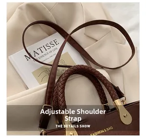 Detail of adjustable shoulder strap and woven handle on brown crocodile texture bag