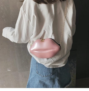 Detail of pink glossy lip-shaped crossbody bag with gold chain and double zipper closure