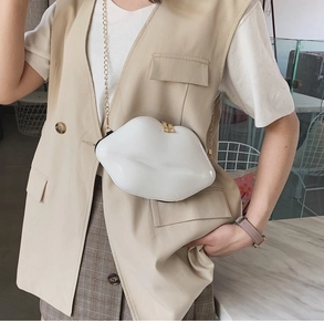 Detail of white lip-shaped crossbody bag with gold chain strap on a stylish model
