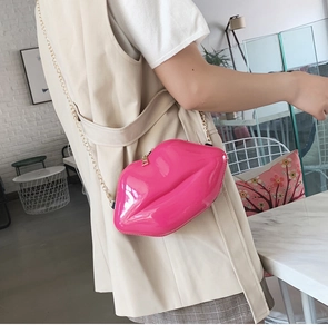 Close-up of pink lip-shaped crossbody bag with gold chain strap on a female model