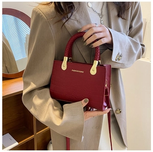 Detail of red stone pattern handbag with woven handle and gold metal hardware