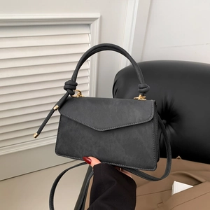Chic black matte crossbody bag with knot handle and gold hardware in lifestyle setting