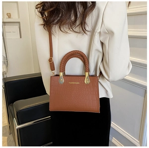 Brown crocodile pattern crossbody bag with woven handles shown in a lifestyle setting