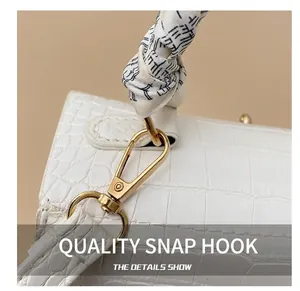 Detail of white crocodile embossed leather bag with gold hardware and silk scarf handle