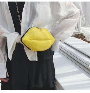 Detail of yellow lip-shaped crossbody bag featuring high-gloss finish and gold chain strap