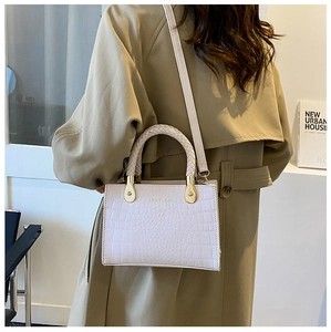 Detail of light beige pink handbag with crocodile texture and woven top handle