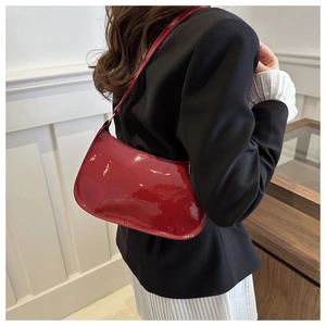 Detalle de bolso hobo en charol rojo brillante con cremallera y correa fina para el hombro