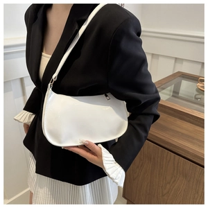 Bolso de hombro blanco minimalista con diseño de media luna lucido por una modelo real
