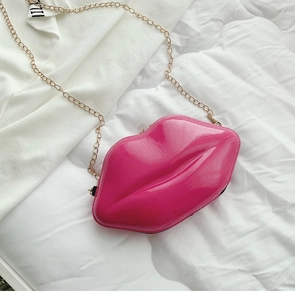 Macro shot of rose red lip-shaped glossy crossbody bag with golden chain strap