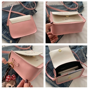 Detail view of pink and beige crossbody bag with cartoon cat and bear charm