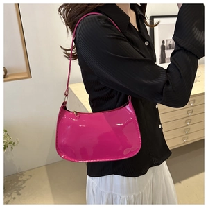 Bolso baguette chic de charol magenta usado como bolso de hombro por una modelo
