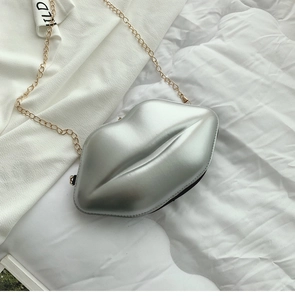 Detail of silver lip-shaped hard shell clutch bag with gold metal chain strap